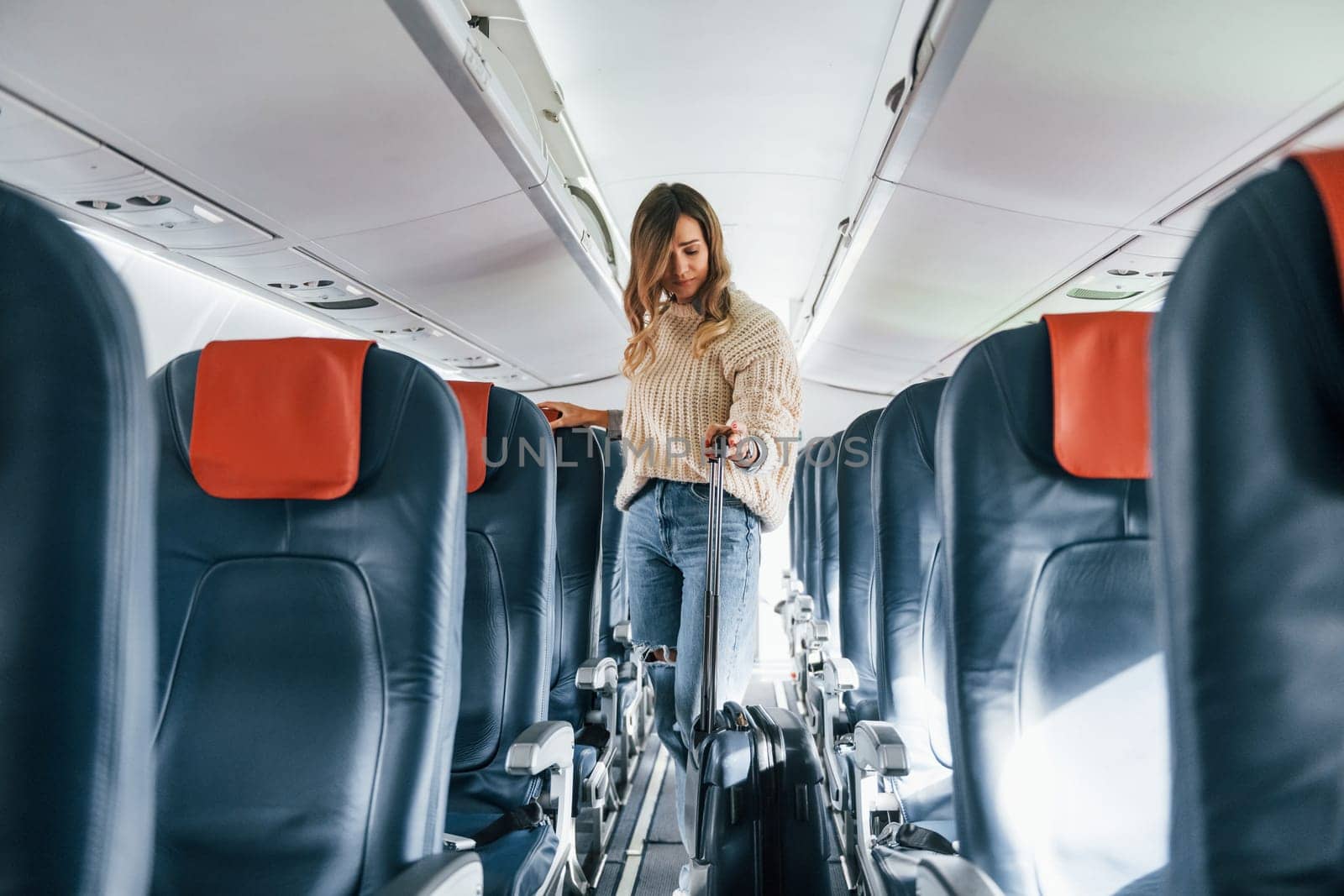 Front view. Young female passanger in casual clothes is in the plane.