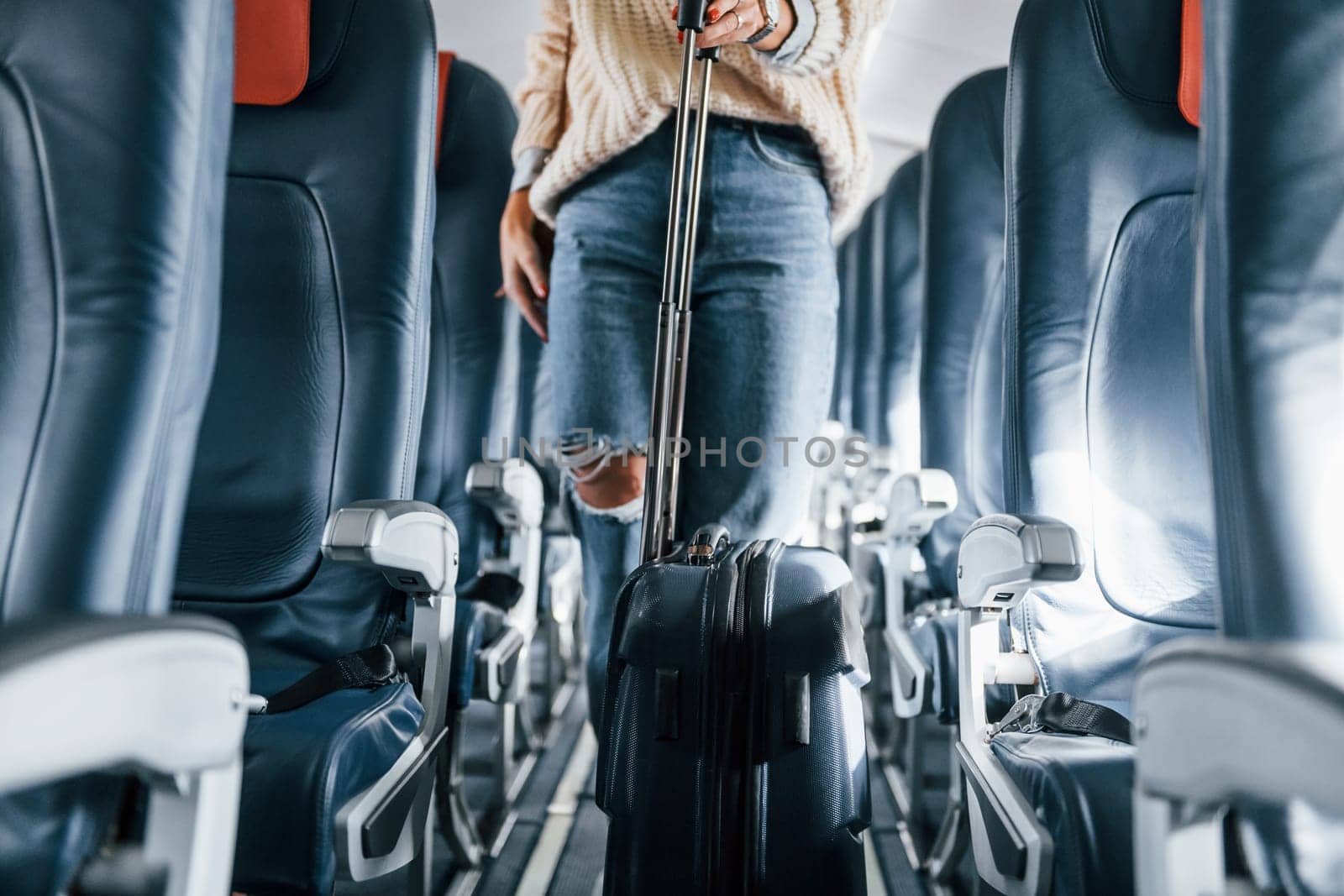 Front view. Young female passanger in casual clothes is in the plane.