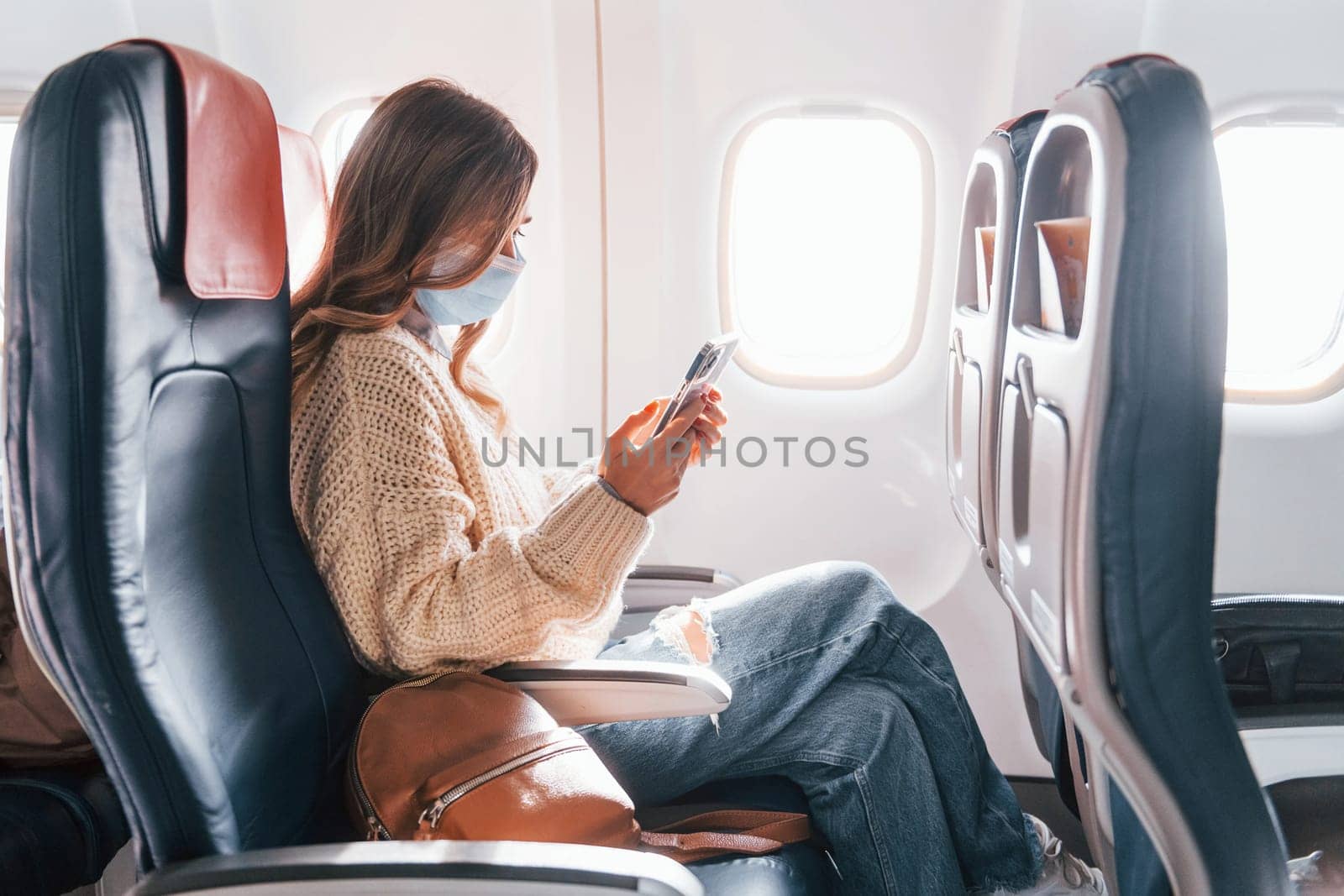 Young tourist. Female passanger in casual clothes is in the plane.