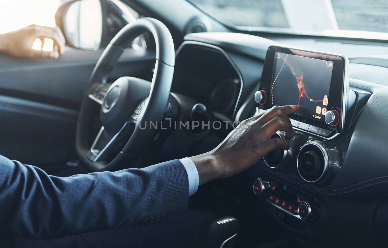 Side view. Young african american businessman in black suit is in the automobile.