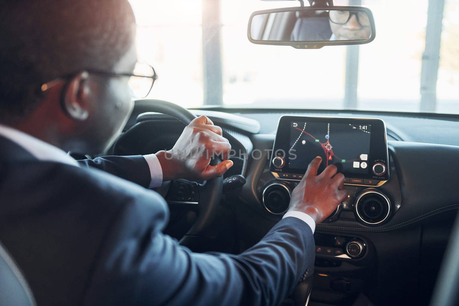 Vehicle interior. Young african american businessman in black suit is in the automobile.