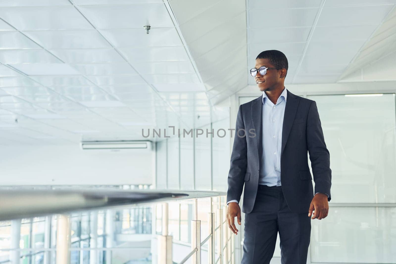 Young african american businessman in black suit is indoors.