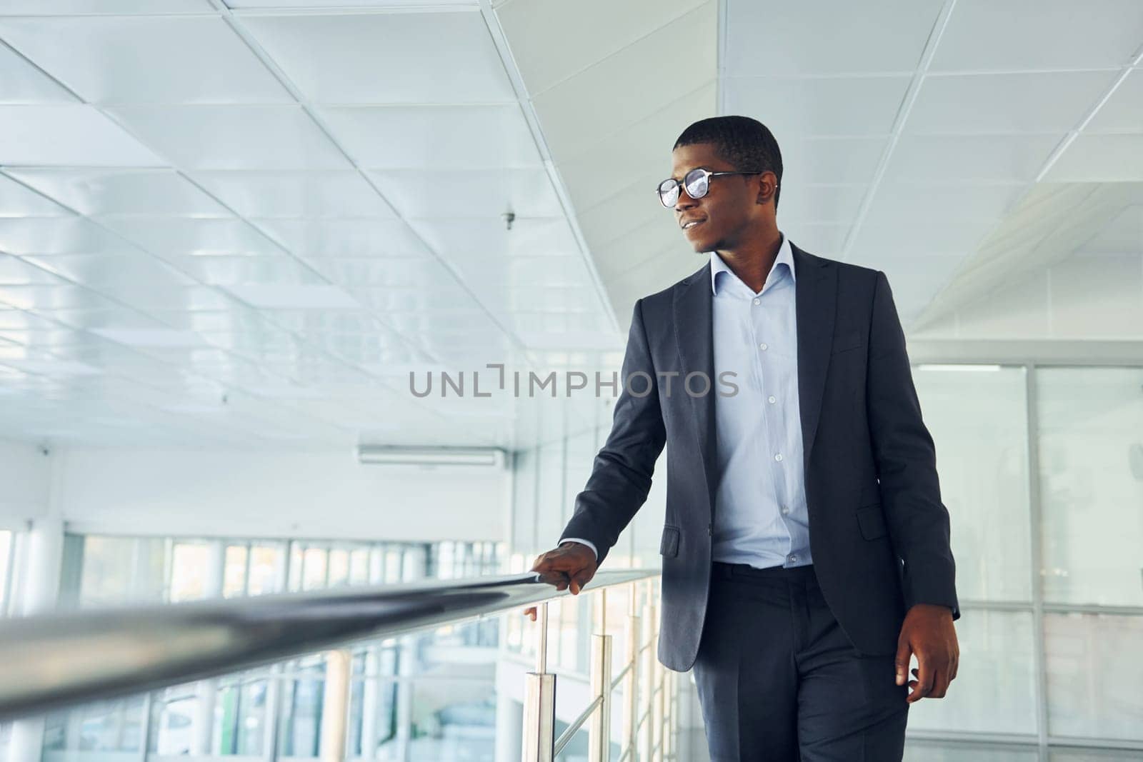 Young african american businessman in black suit is indoors.