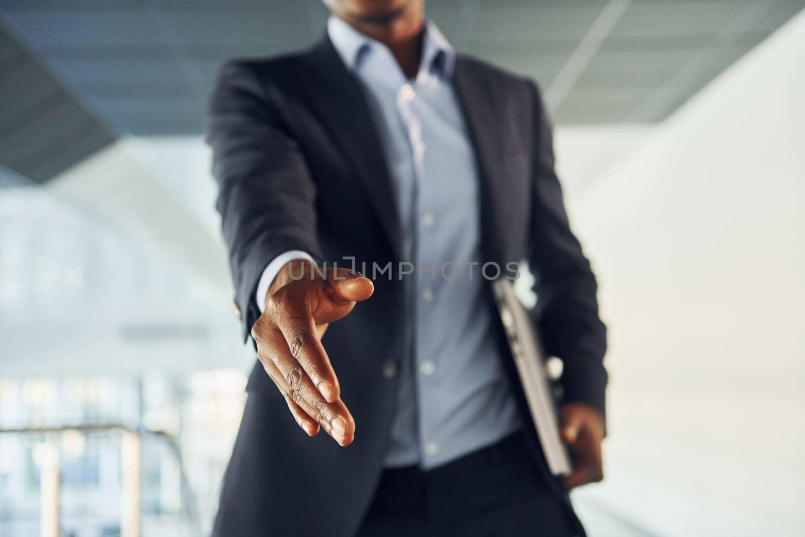 Successfull agreement. Young african american businessman in black suit is indoors.