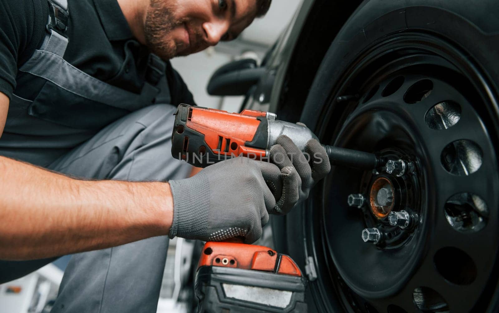 Modern vehicle. Man in uniform is working in the autosalon at daytime.