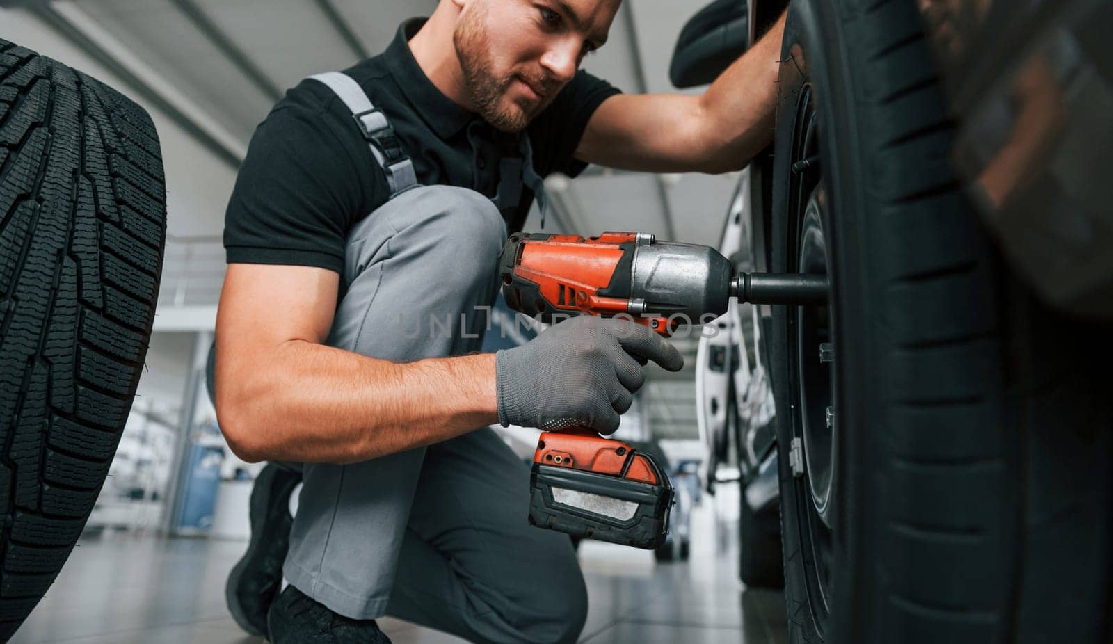 Modern vehicle. Man in uniform is working in the autosalon at daytime.