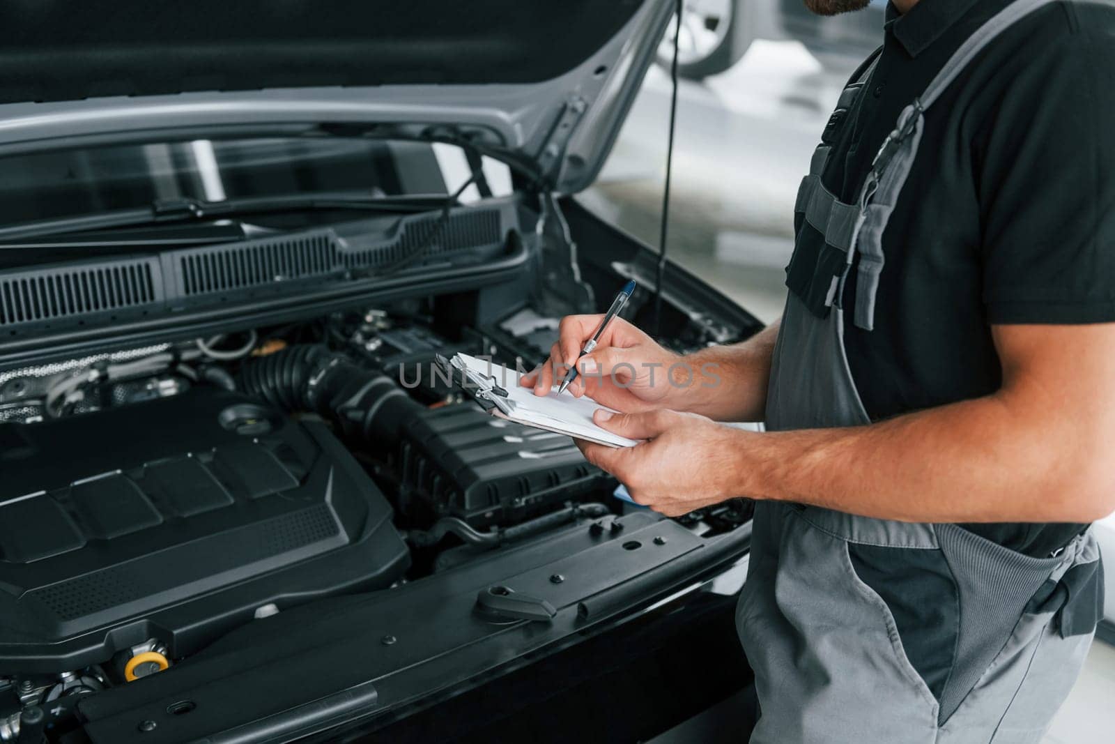Modern vehicle. Man in uniform is working in the autosalon at daytime.