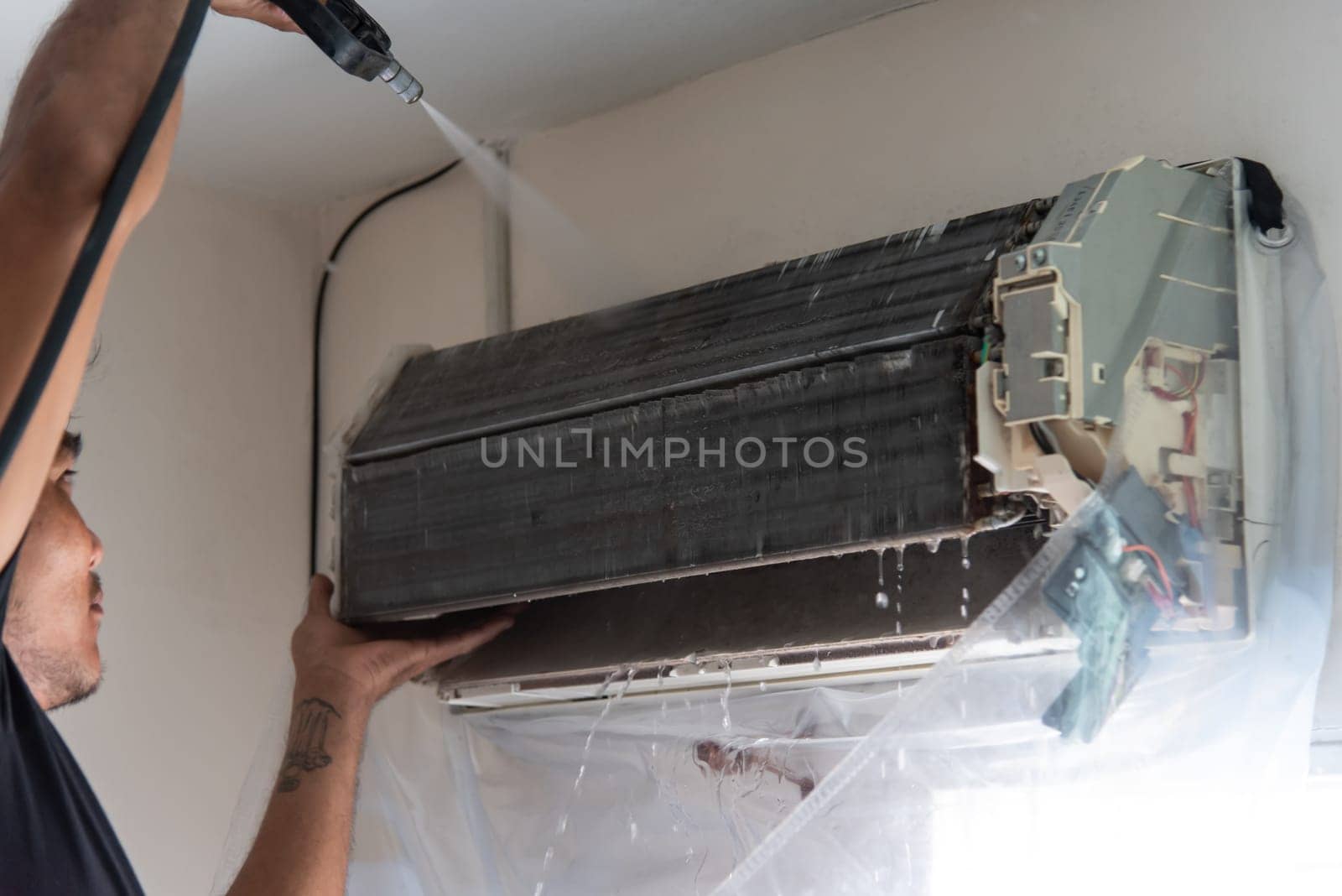 Bangkok, Thailand - July 22, 2017 : Unidentified worker to cleaning coil cooler of air conditioner by water for clean a dust on the wall in customer home when maintenance service