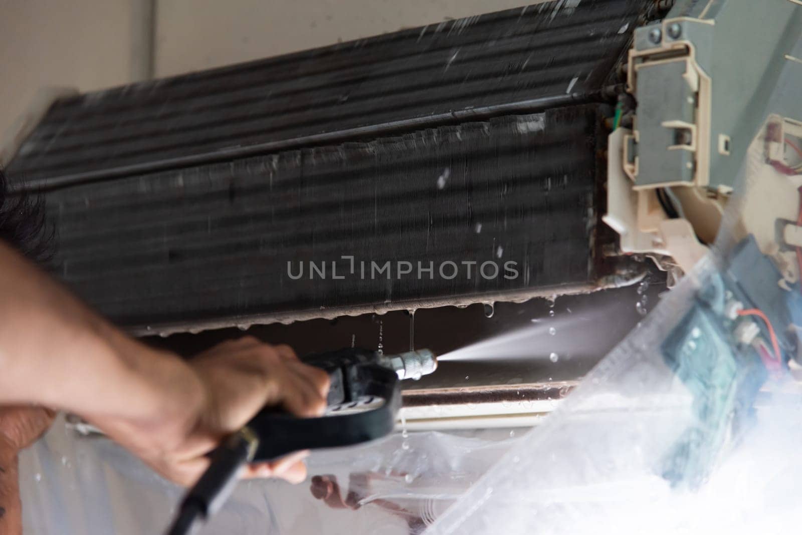 Bangkok, Thailand - July 22, 2017 : Unidentified worker to cleaning coil cooler of air conditioner by water for clean a dust on the wall in customer home when maintenance service