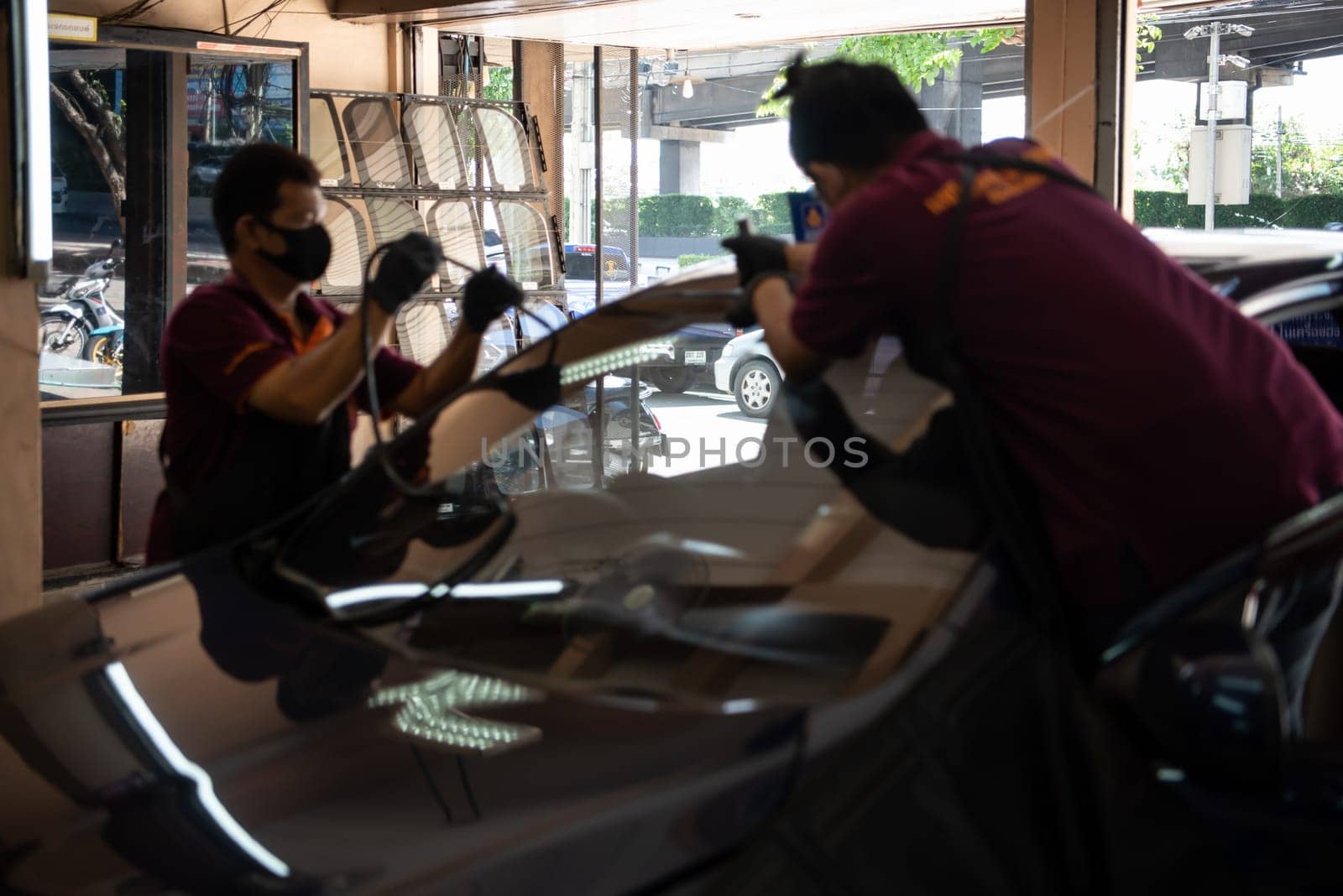 Bangkok, Thailand - July 5, 2021 : Unidentified car mechanic or serviceman install and fitting a new windscreen or windshield for fix and repair problem at car garage or repair shop