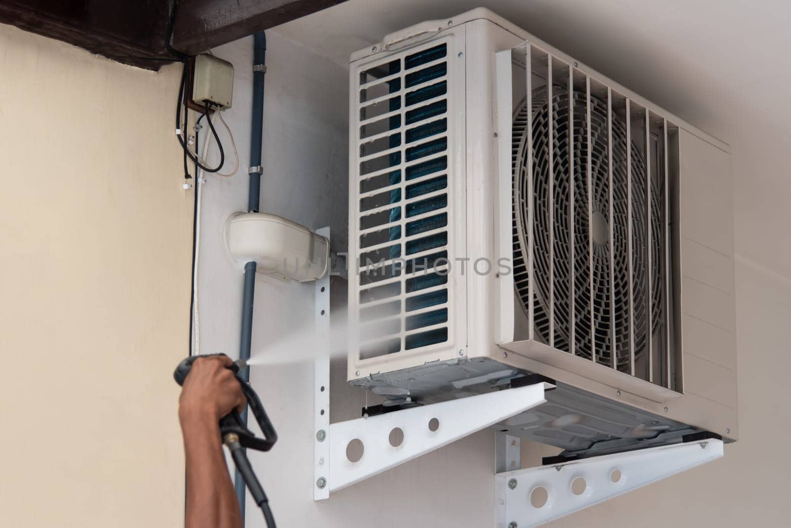 Worker to cleaning coil cooler of air conditioner by water for clean a dust on the wall in customer home when maintenance service