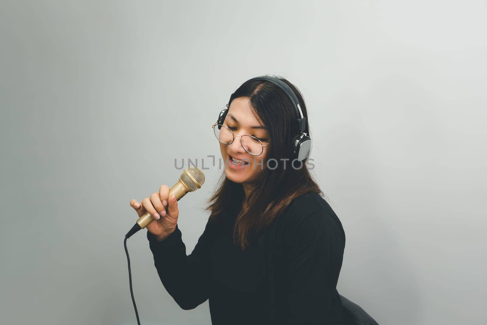 Beautiful asian woman (LGBTQ) is a singer. She enjoying sing a song or karaoke in music studio with microphone condenser and headphones for fun or voice creative