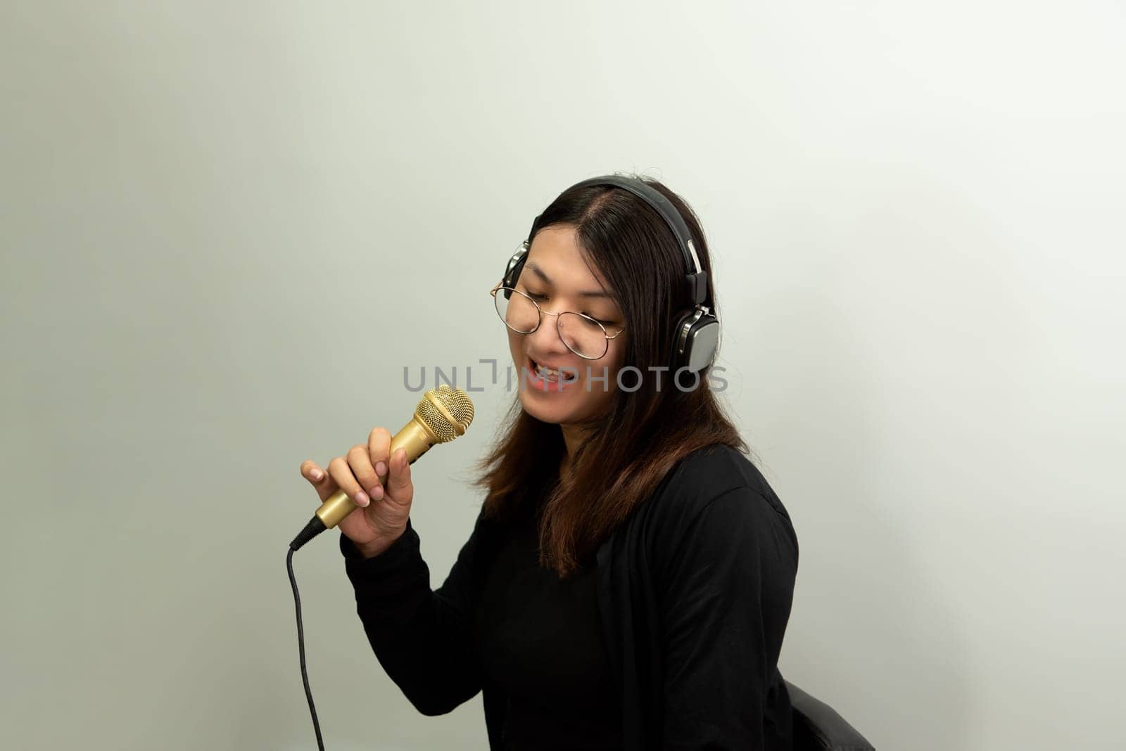 Beautiful asian woman (LGBTQ) is a singer. She enjoying sing a song or karaoke in music studio with microphone condenser and headphones for fun or voice creative