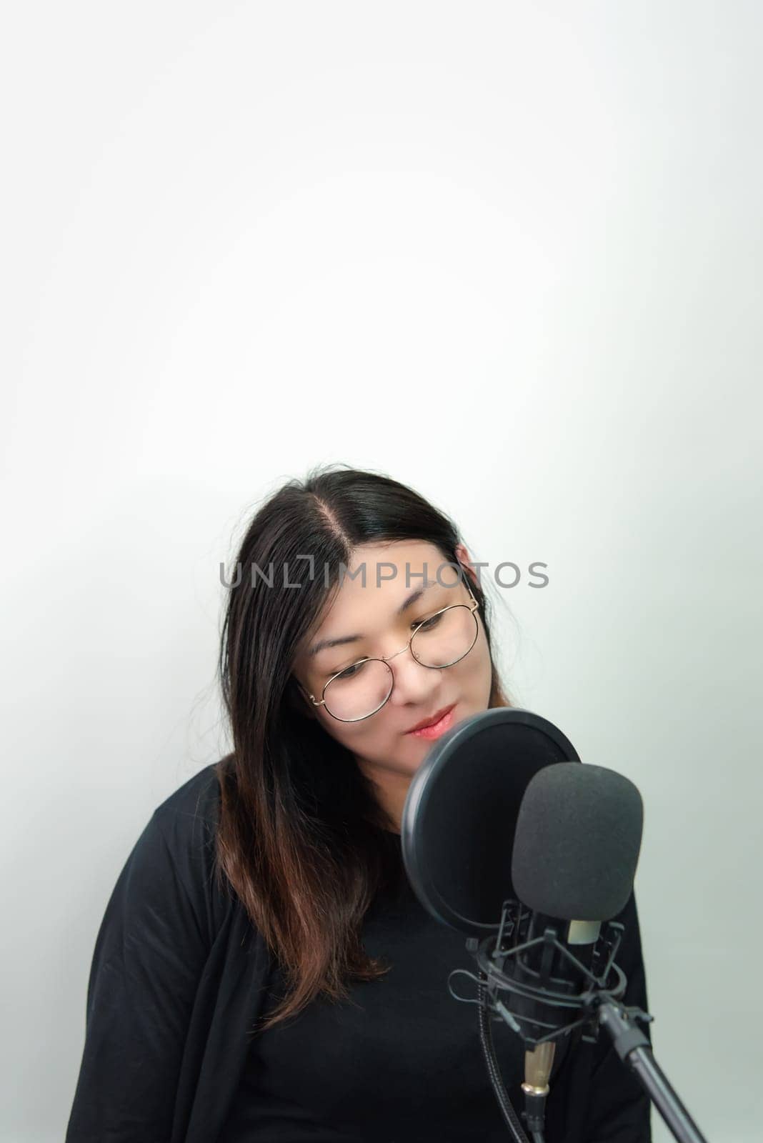 Beautiful asian woman (LGBTQ) is a singer. She enjoying sing a song or karaoke in music studio with microphone condenser and headphones for fun or voice creative