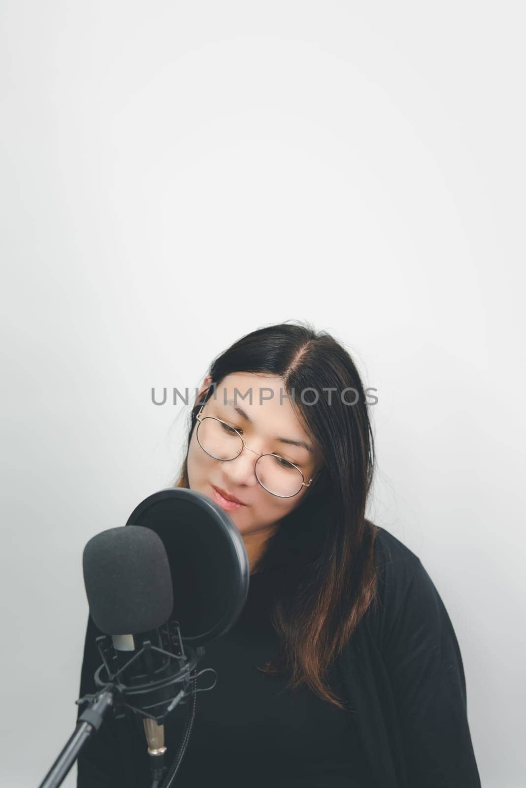 Beautiful asian woman (LGBTQ) is a singer. She enjoying sing a song or karaoke in music studio with microphone condenser and headphones for fun or voice creative