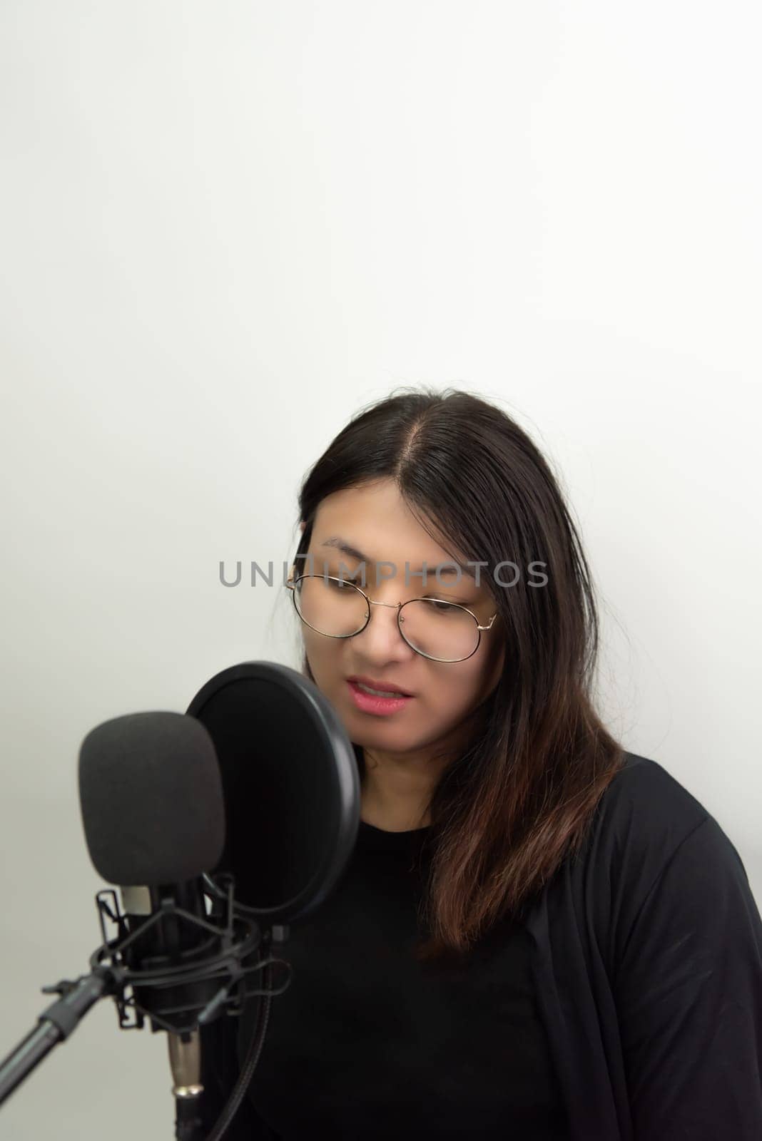 Beautiful asian woman (LGBTQ) is a singer. She enjoying sing a song or karaoke in music studio with microphone condenser and headphones for fun or voice creative