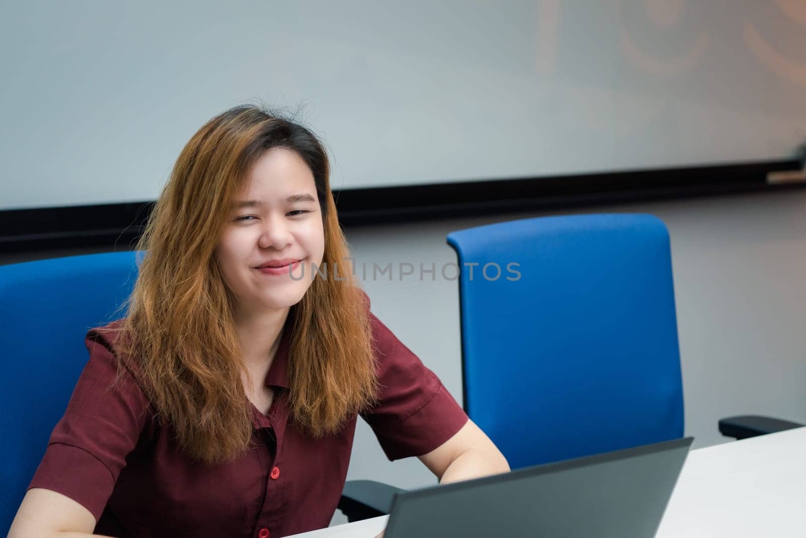 Asian woman is student, businesswoman working by computer notebook, laptop in office meeting room with whiteboard in background with happy and relax emotion in concept working woman, success in life