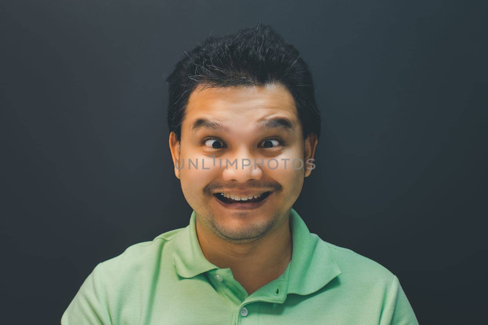 Asian man 40s smile have a crazy squinting gesture with confusion and problems concept on black background dark style