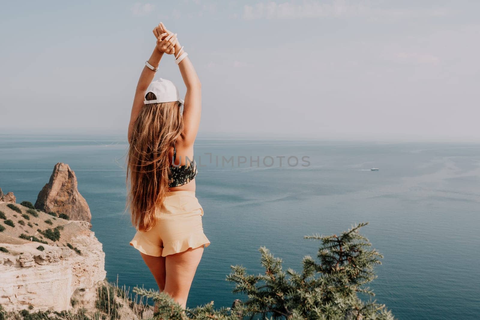 Woman travel sea. Happy tourist taking picture outdoors for memories. Woman traveler looks at the edge of the cliff on the sea bay of mountains, sharing travel adventure journey by panophotograph