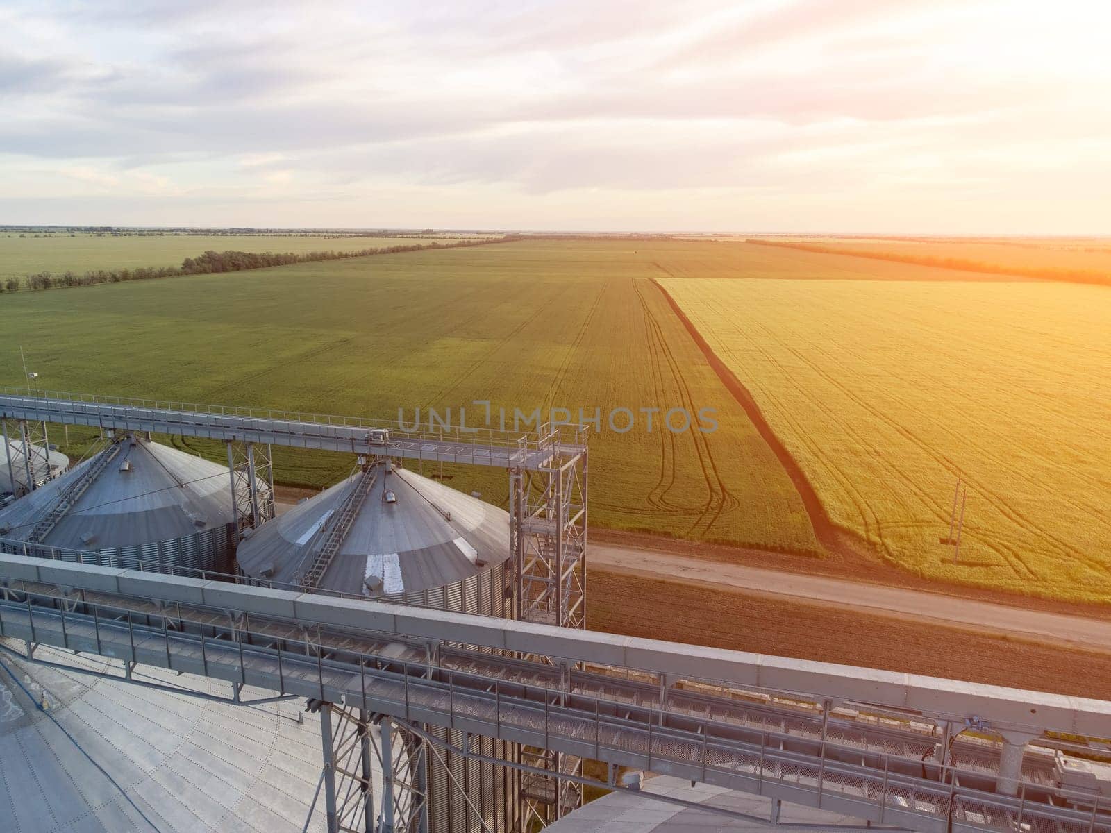 Modern metal silos on agro-processing and manufacturing plant. Aerial view of Granary elevator processing drying cleaning and storage of agricultural products, flour, cereals and grain. Nobody. by panophotograph