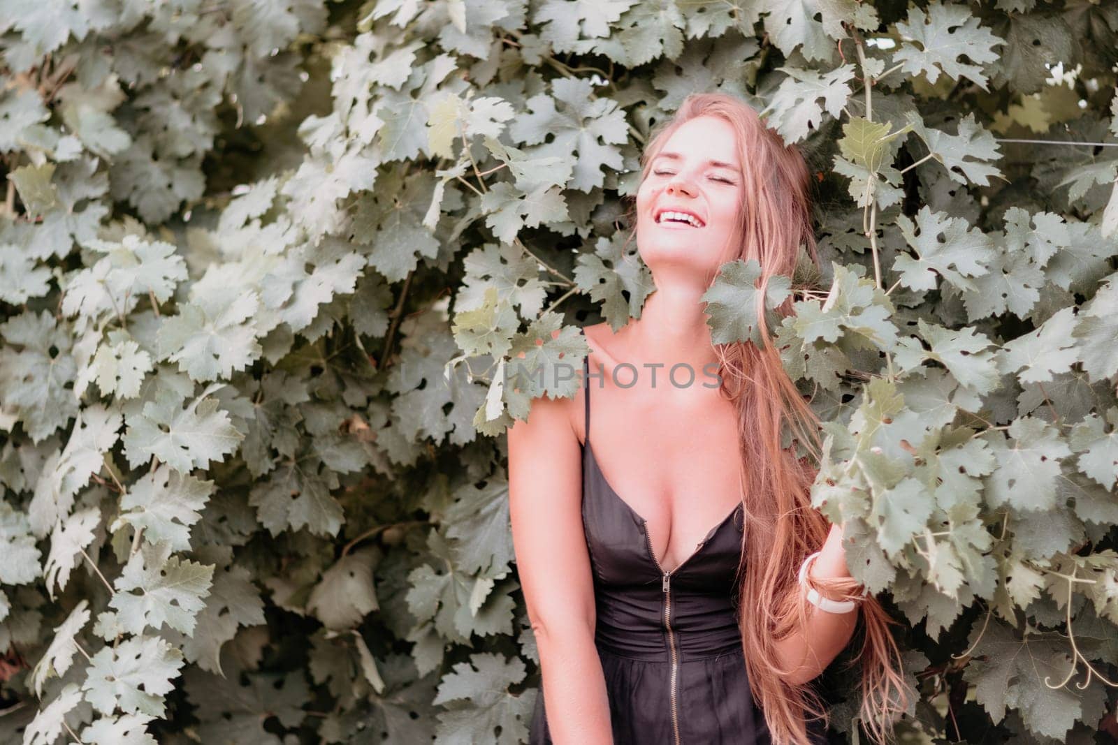 Woman at autumn winery. Portrait of happy woman holding glass of wine and enjoying in vineyard. Elegant young lady in hat toasting with wineglass smiling cheerfully enjoying her stay at vineyard