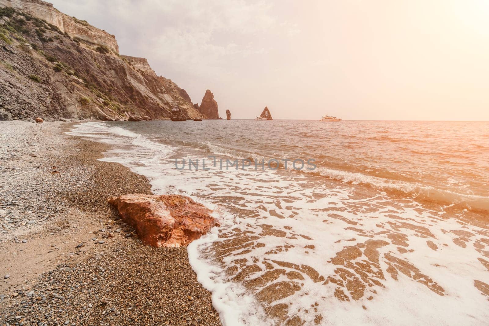 Large red jasper rock on the beach, with the sea in the background. Big Red Jasper Stone Close Up by panophotograph