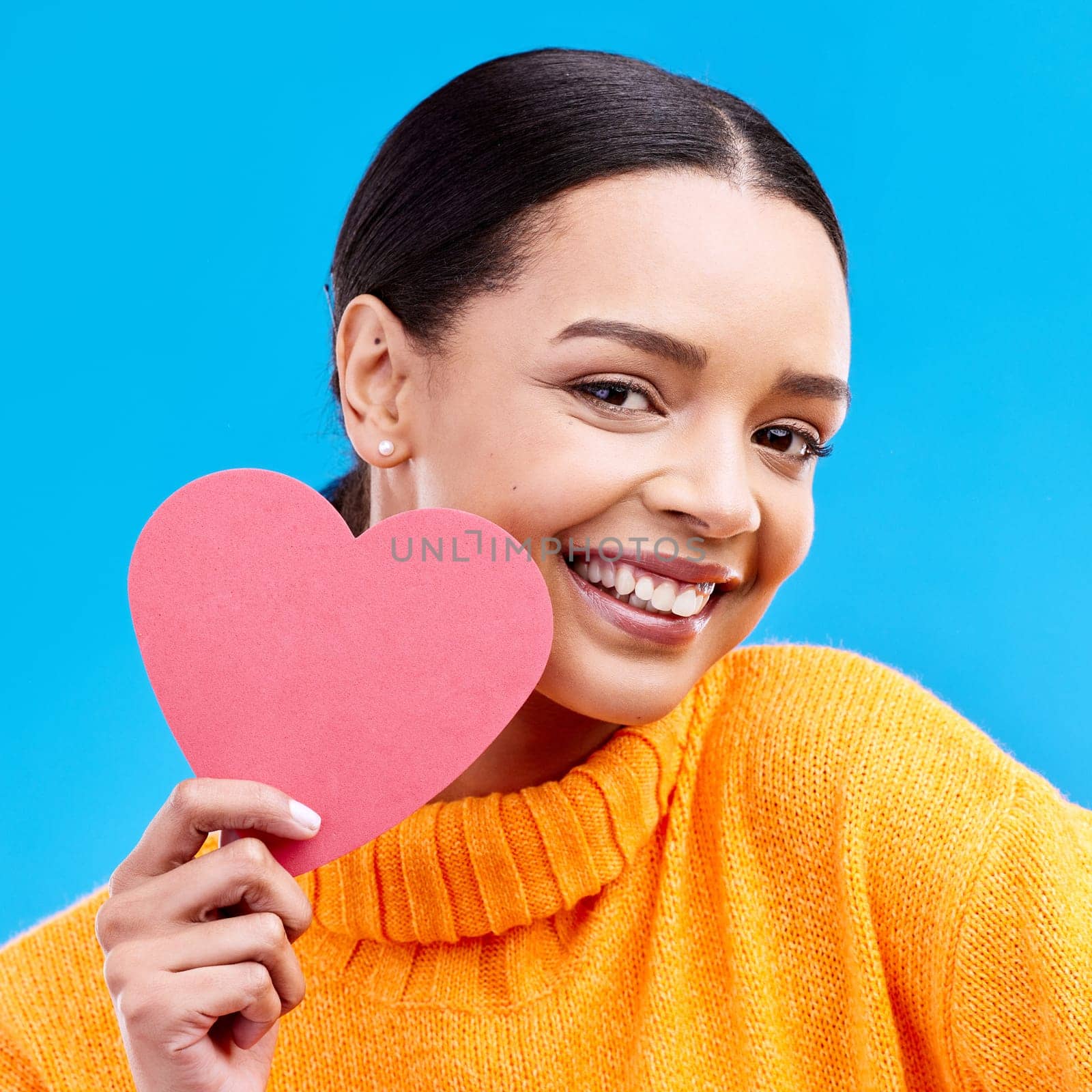 Paper heart, love and portrait of happy woman in studio, blue background and romantic sign. Female model, emoji shape and smile for care, support and thank you for kindness, valentines day or emotion.