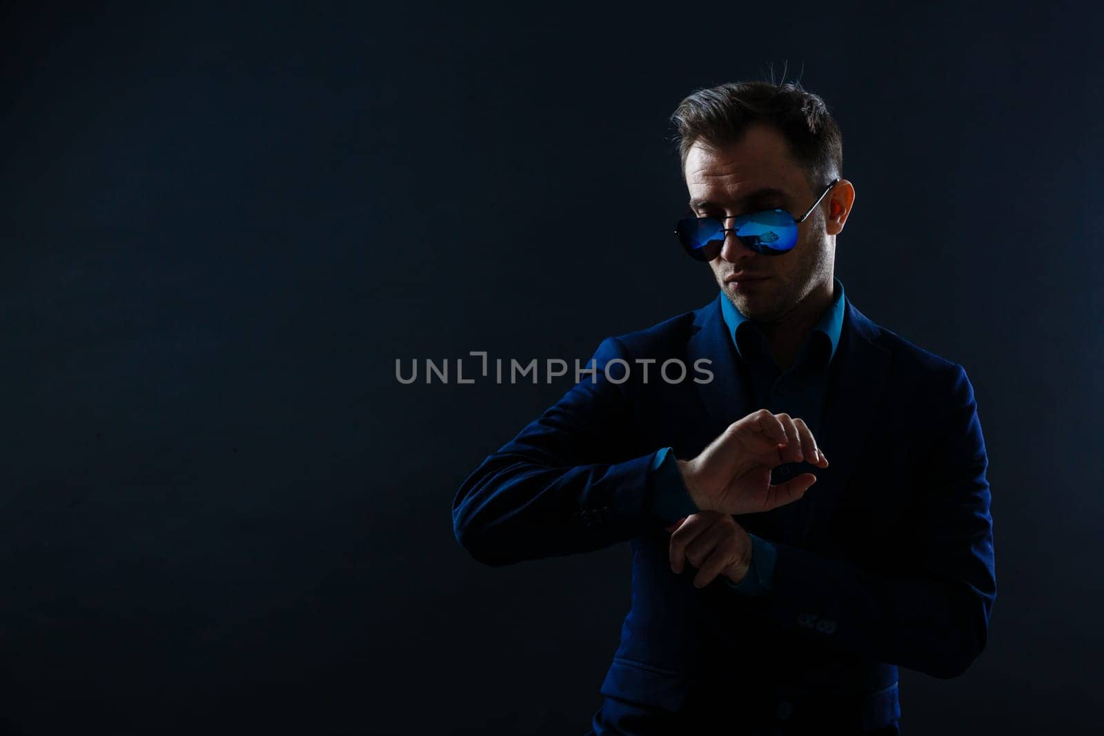 Portrait of attractive cheerful gentleman posing isolated over dark color background.