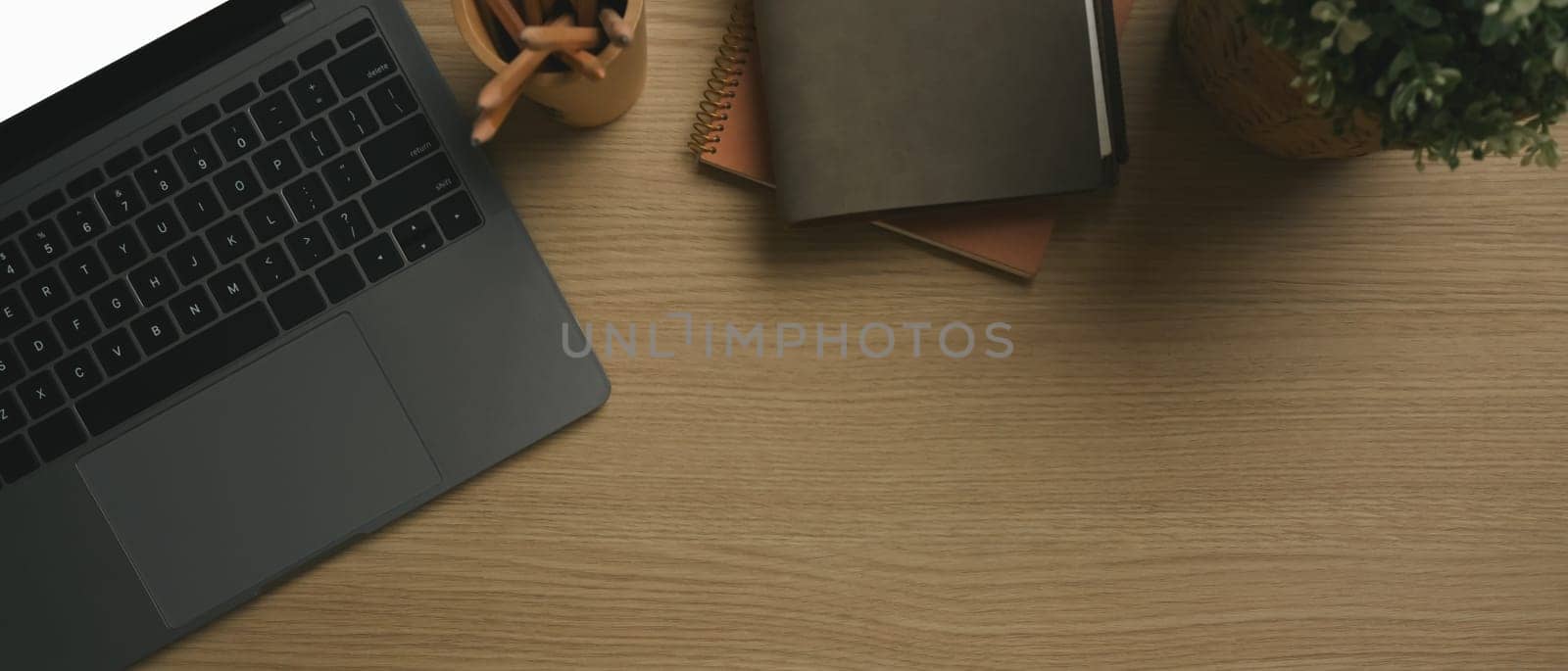 Top view of laptop computer, stationery and cup of coffee on wooden working desk. Copy space for your text.