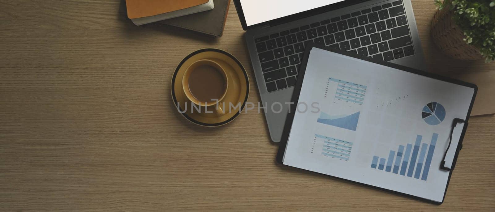Top view of laptop computer, stationery and cup of coffee on wooden working desk. Copy space for your text by prathanchorruangsak