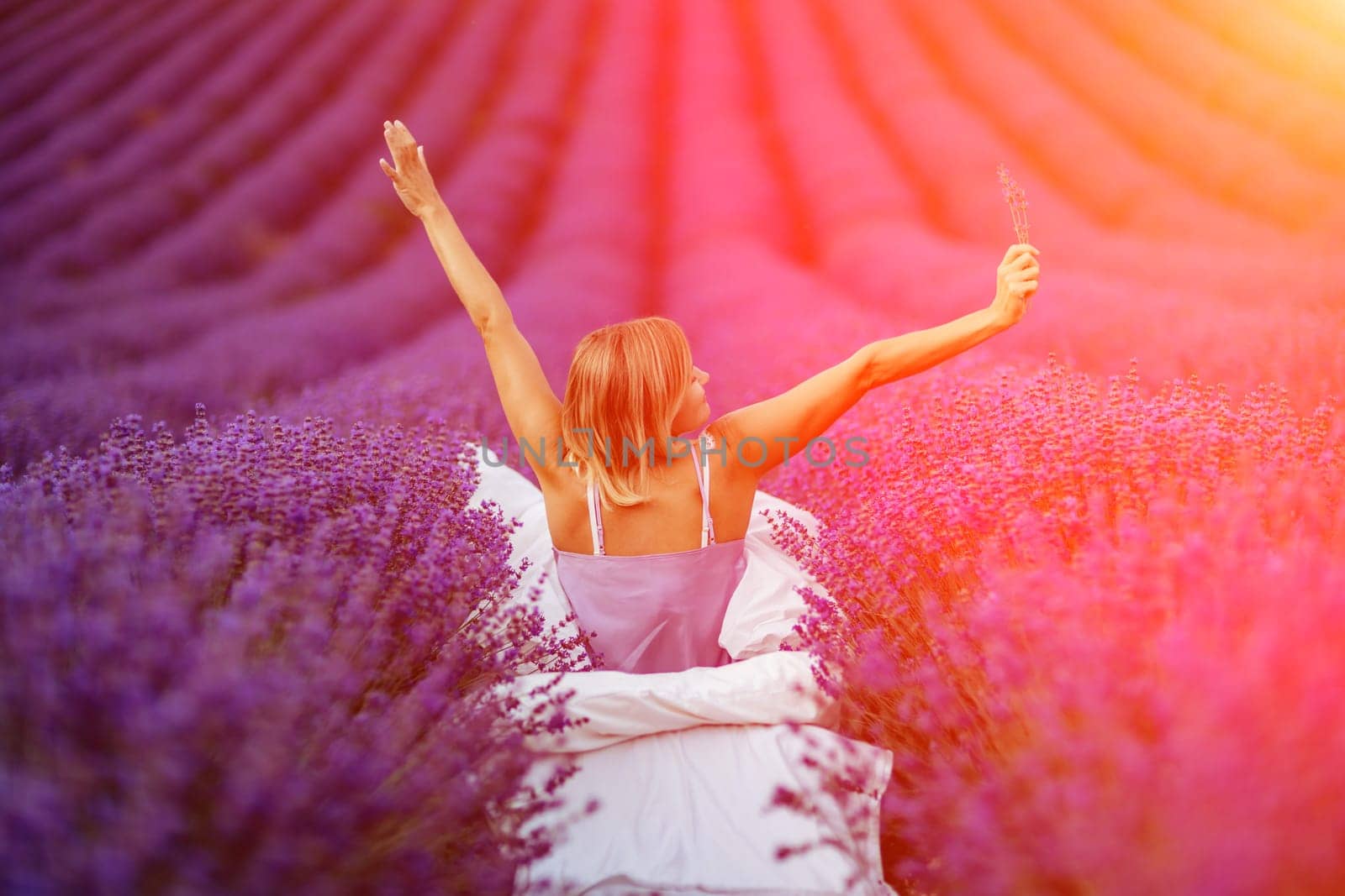 A middle-aged woman sits in a lavender field and enjoys aromatherapy. Aromatherapy concept, lavender oil, photo session in lavender by Matiunina