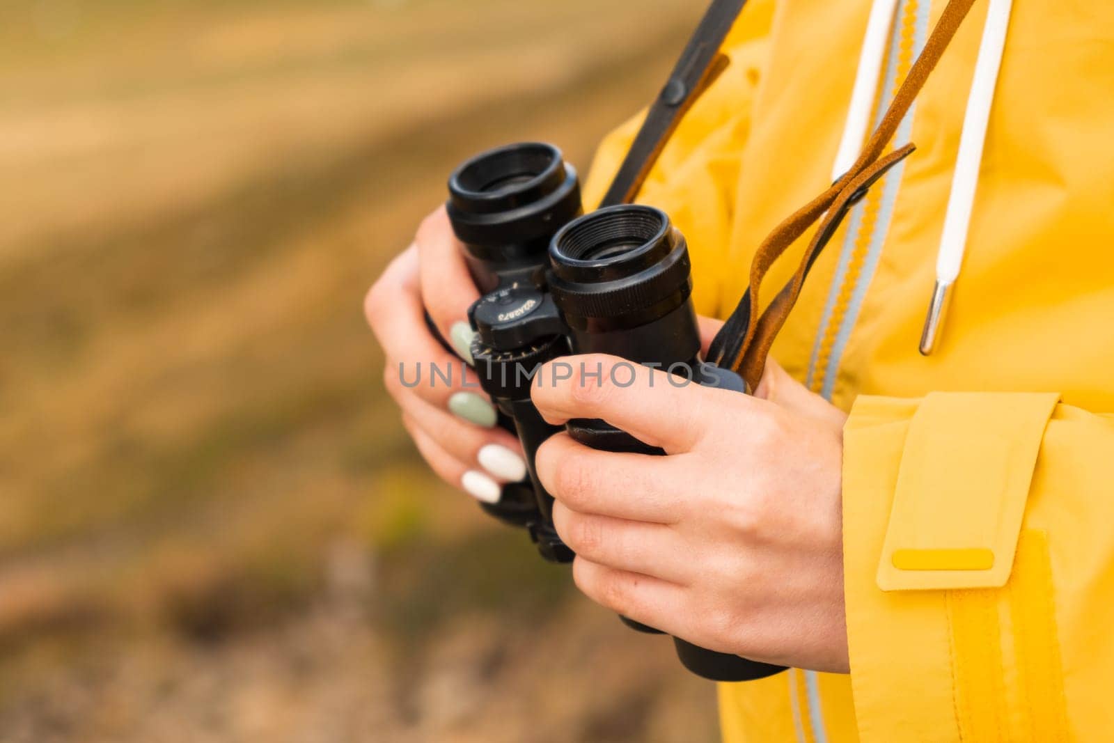 Close up binoculars in woman hands for looking in distance by vladimka