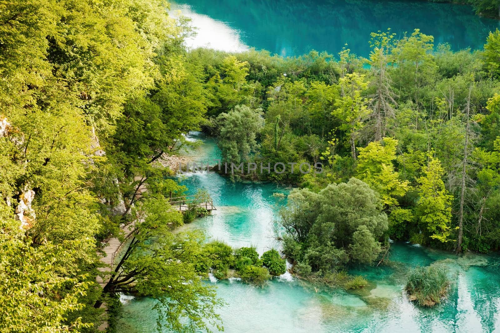 Breathtaking nature of deep blue lake surrounded by green forests on hilly banks. Natural park reserve as tourist attraction on Plitvice lakes upper view