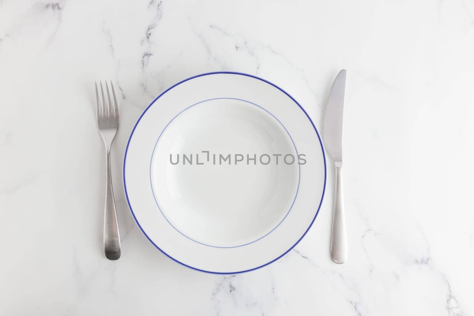 Empty white soup plate with blue stripe top view on a white background