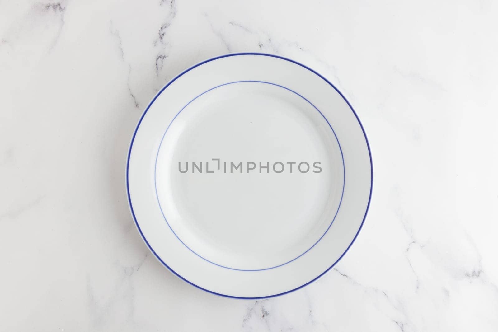 Empty white dinner plate with blue stripe top view on a white background