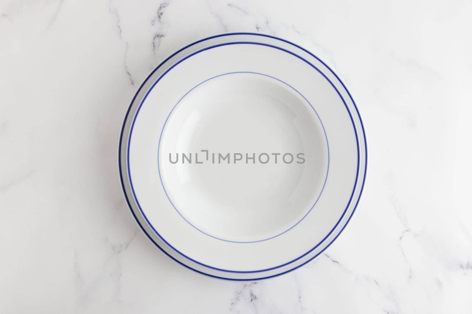 Empty white dinner plate with blue stripe top view on a white background