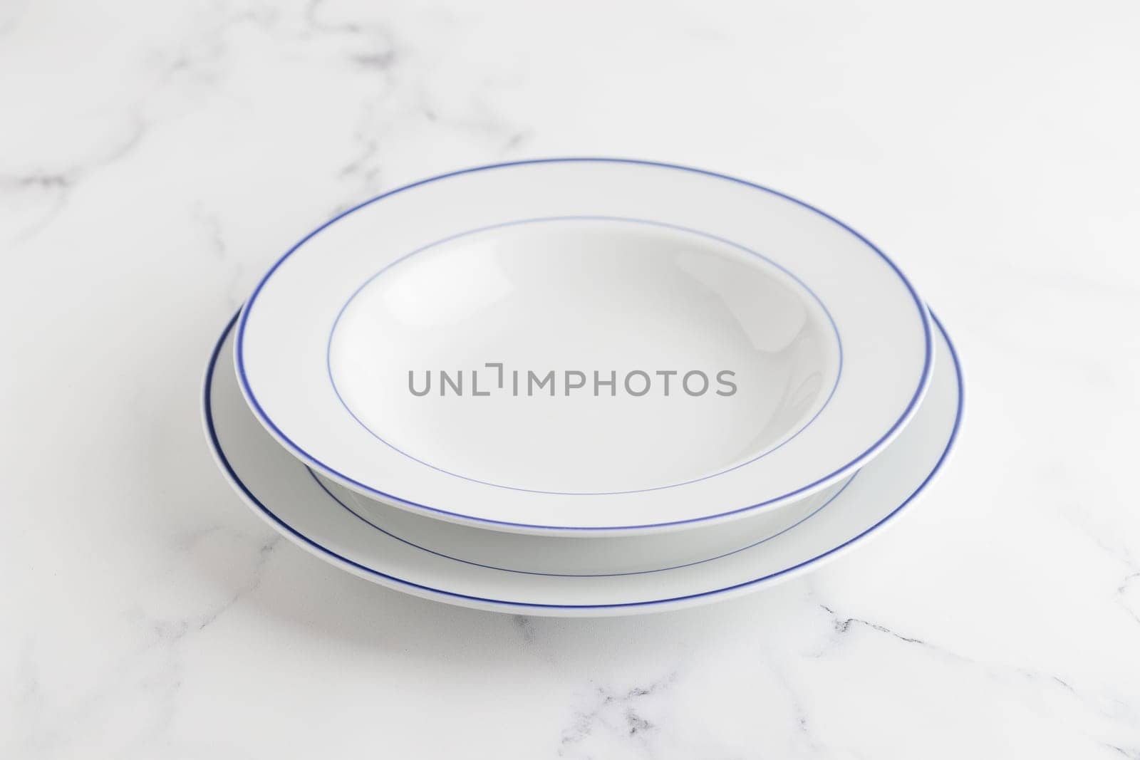 Empty white soup plate with blue stripe on a white background