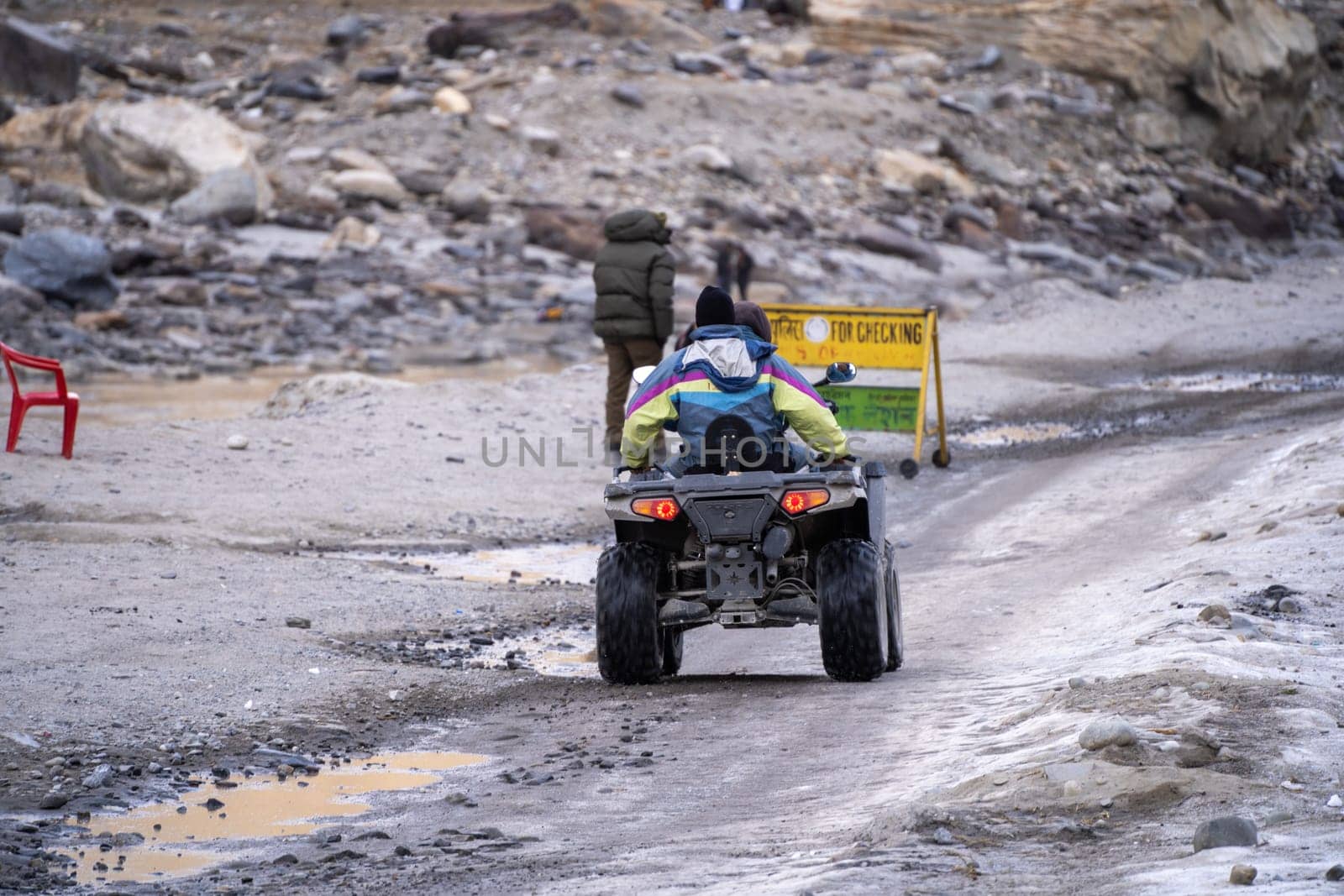 Manali, India - circa 2023: crowd of people at lahul spiti showing small food outlets, adventure sports with family riding ATV on the snow covered road with himalay peaks in the distance