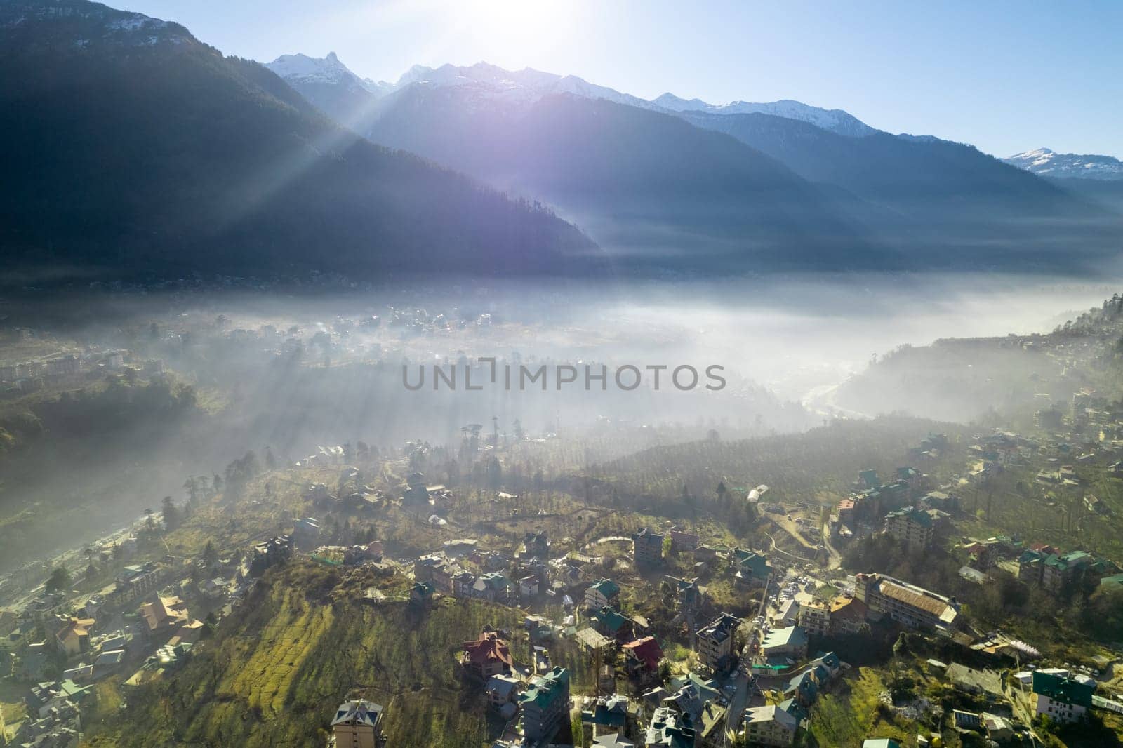 aerial drone shot gaining height over fog covered valley town of manali hill station with himalaya range in distance showing this popular tourist destination in India