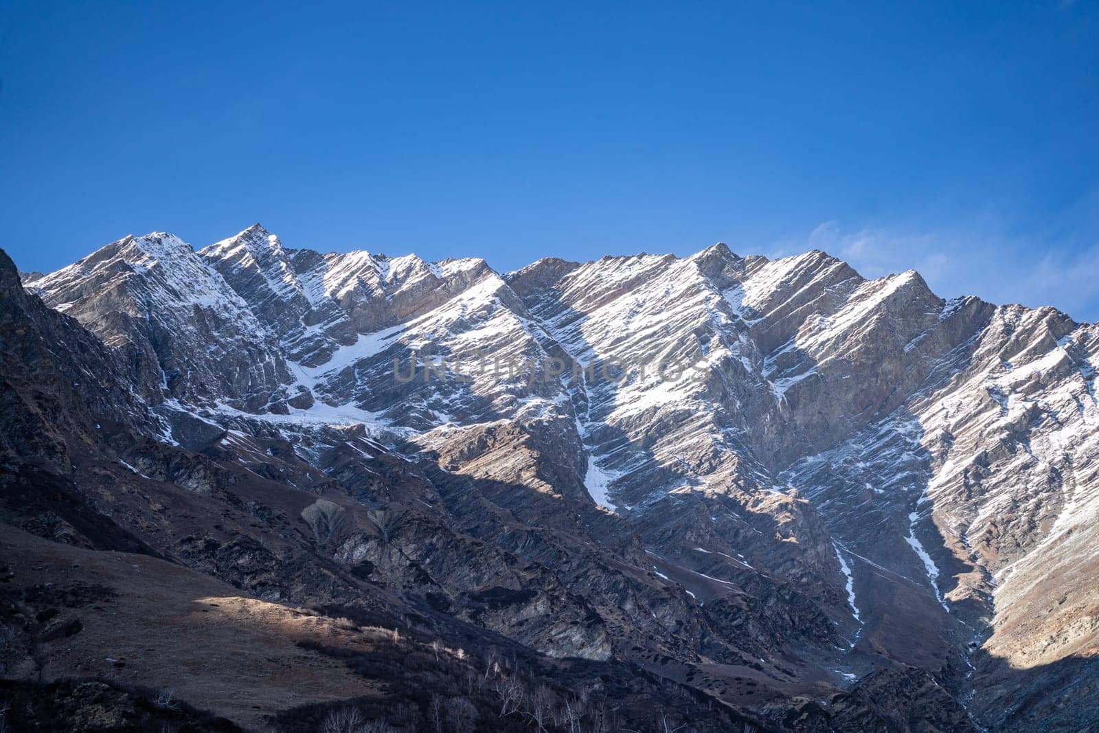 rocky himalayan peaks with snow covering the top against the blue sky showing the beauty of leh ladakh spiti valley in India