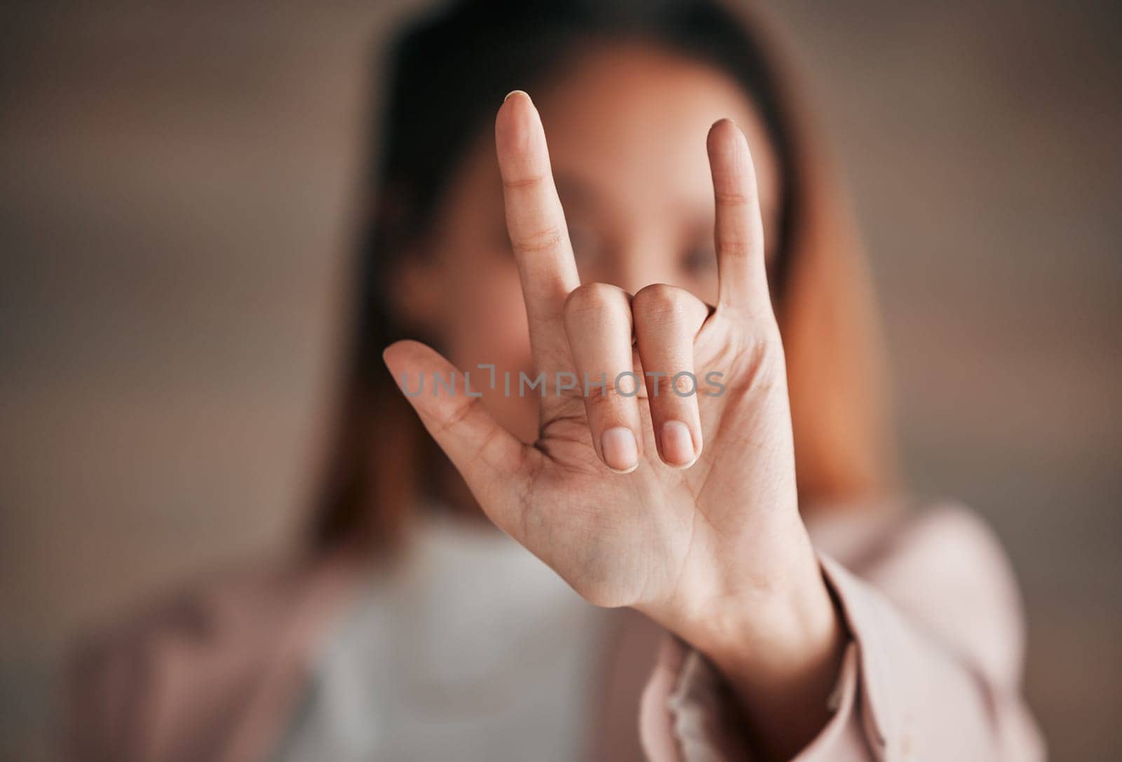 Hand, sign language and love with a person closeup in studio on a blurred background for communication. Emoji, icon or affection and an adult indoor to gesture romance with a fingers icon signal by YuriArcurs