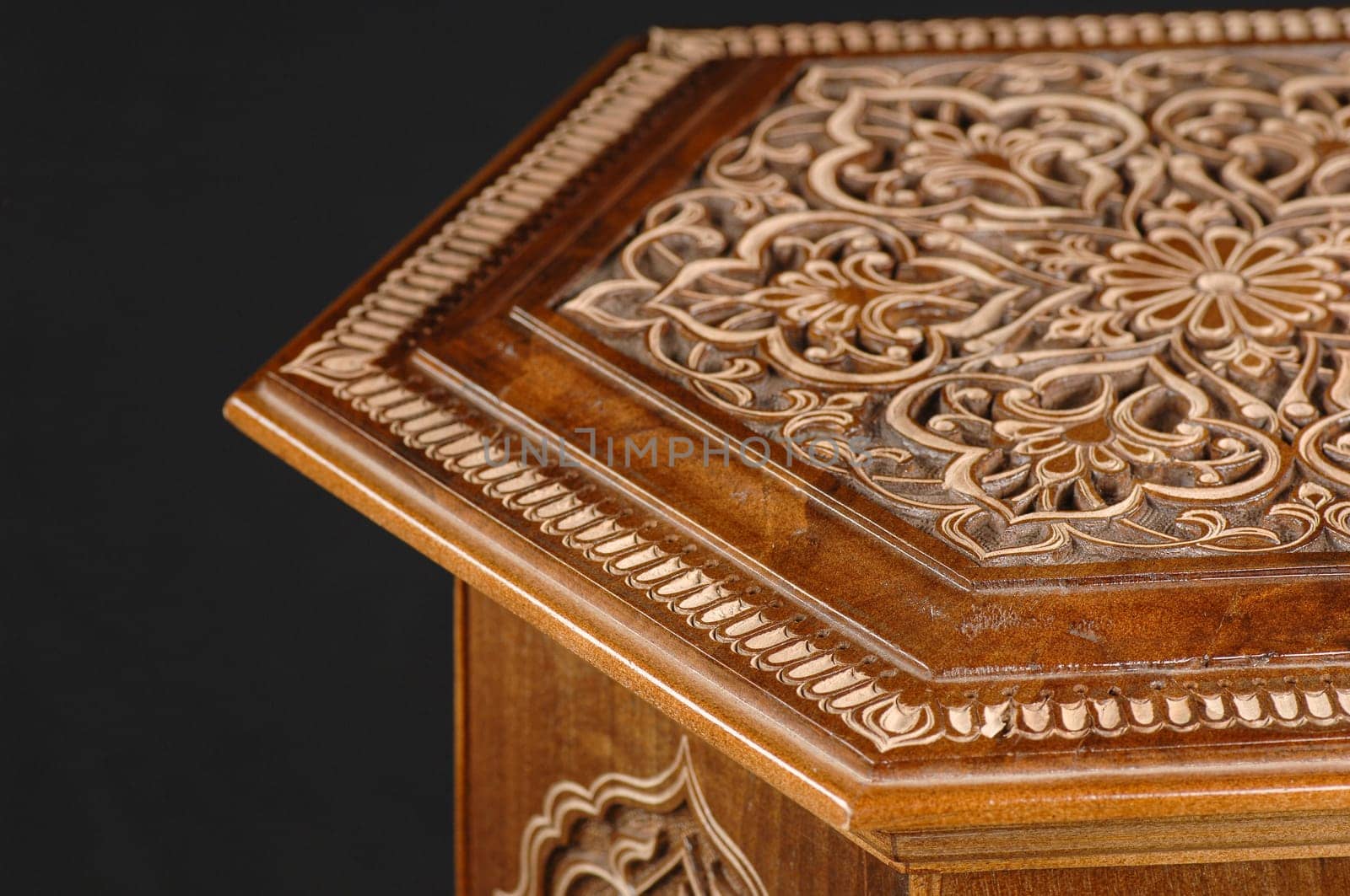 The close-up vintage oriental wooden table with the artistic carving on a black background, Uzbekistan