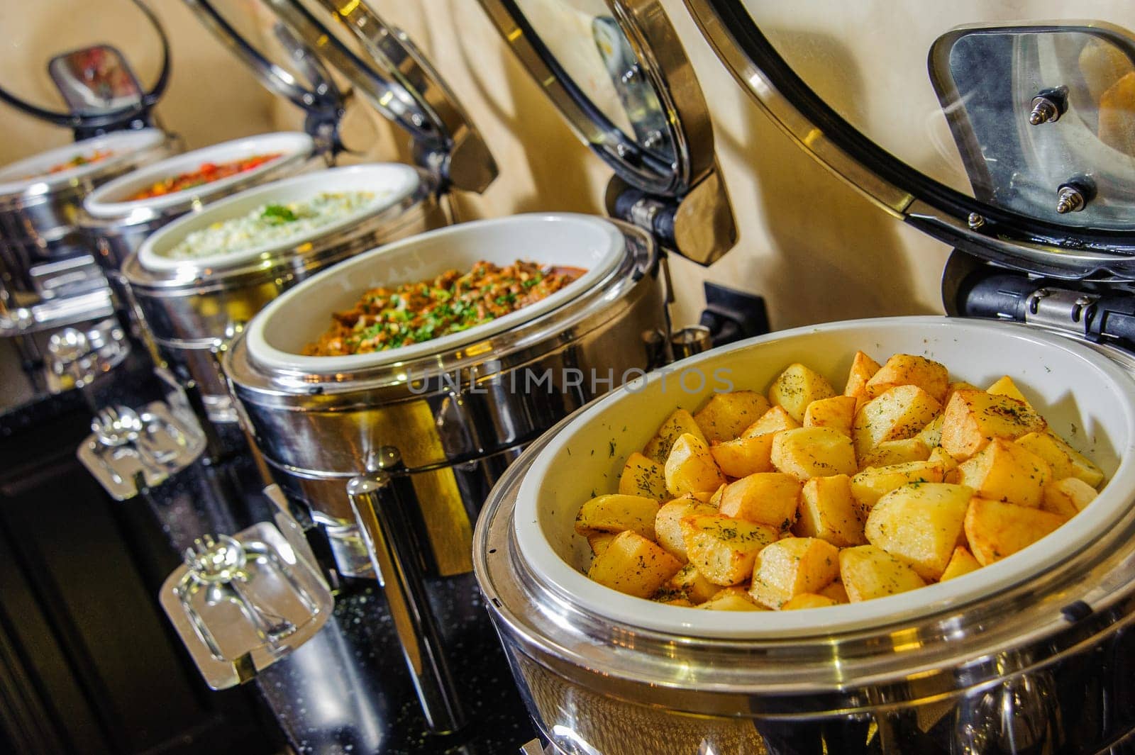 A buffet table with containers full of potato and meat dishes