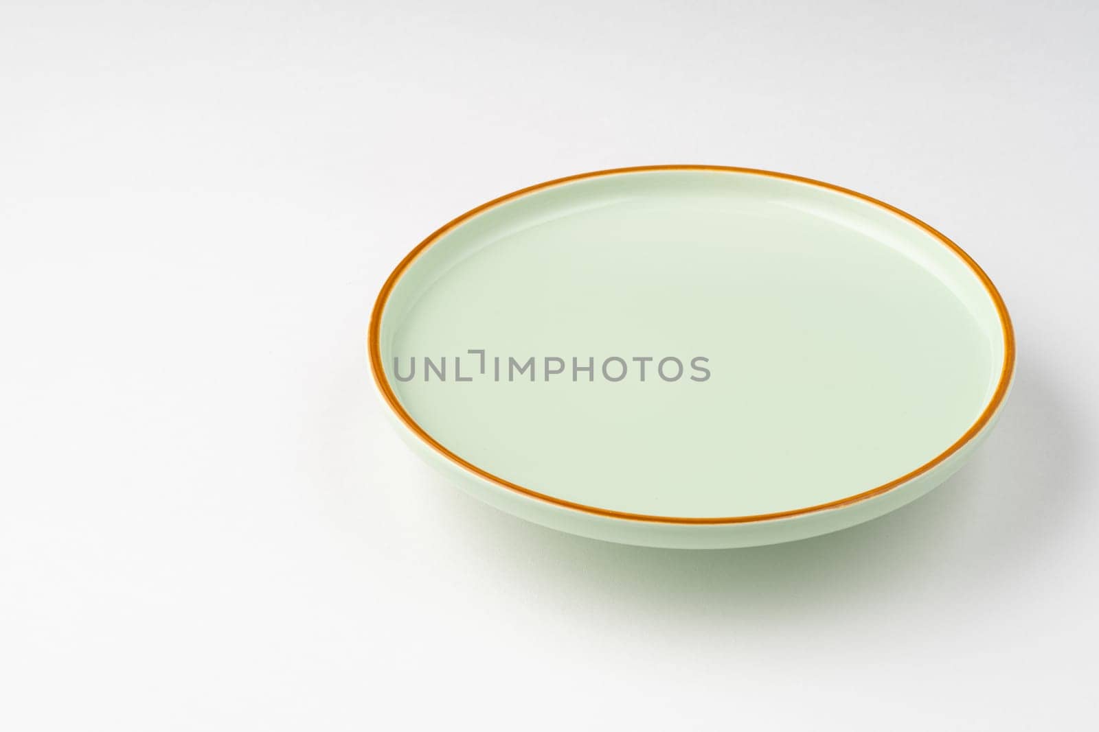 The pastel green ceramic plate with orange outlines on a white background