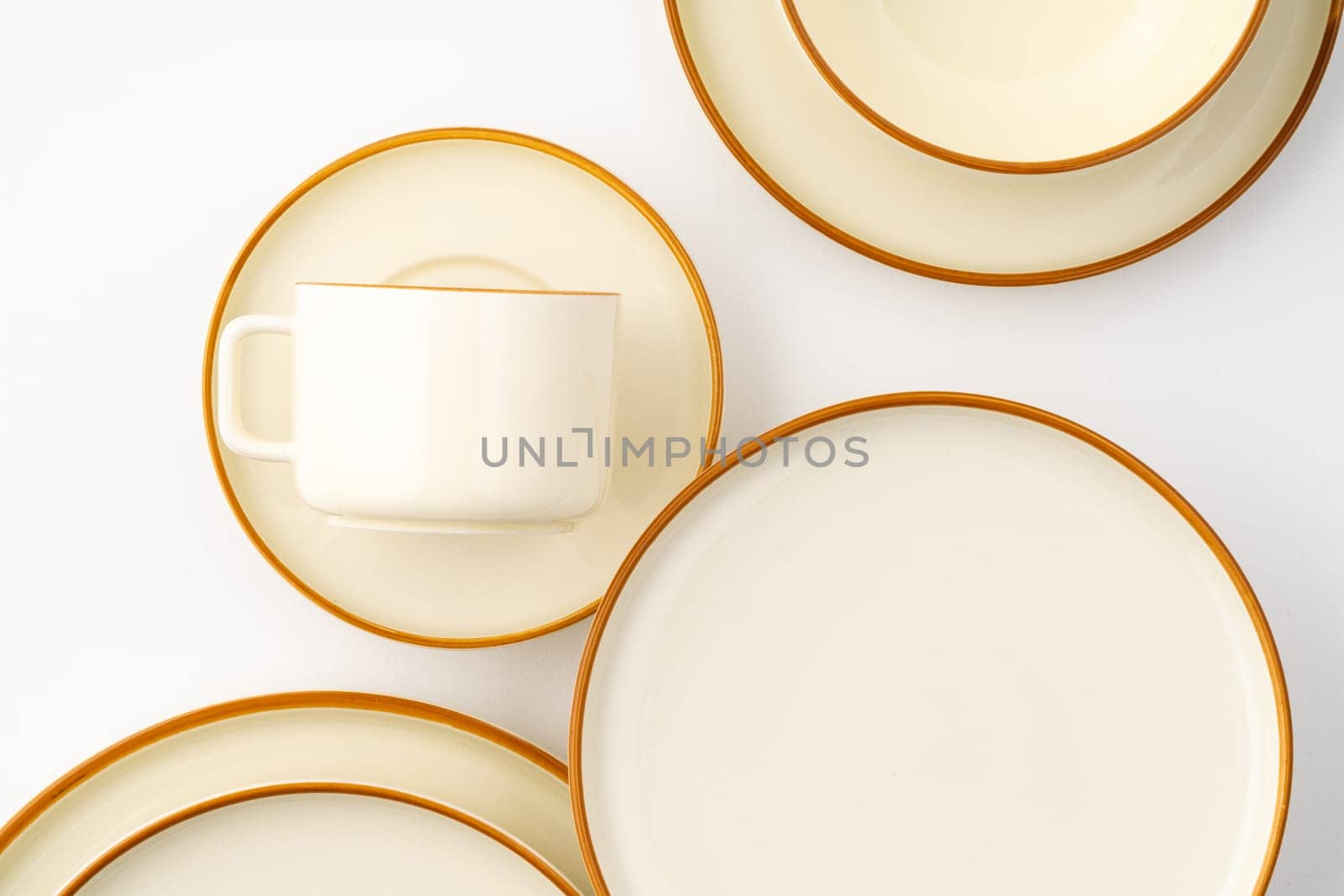 A set of white and brown ceramic plate and cup on a white background. Top view