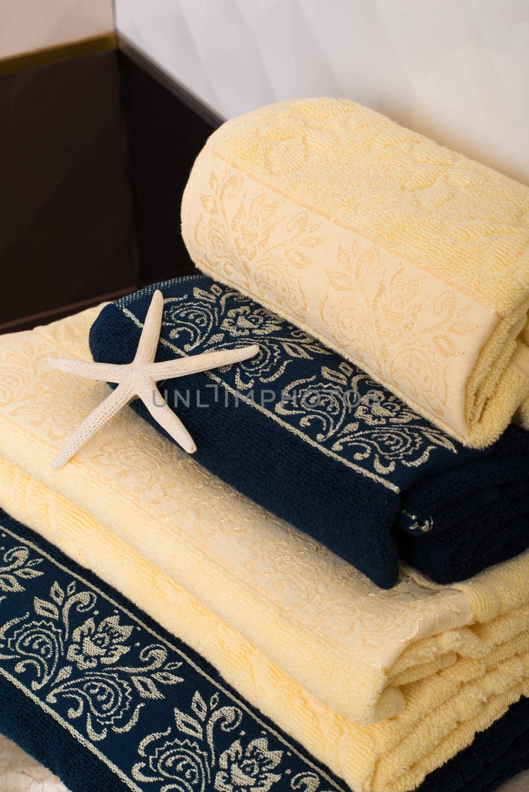 A vertical shot of a stack of folded yellow and navy blue bamboo towels and a starfish decoration