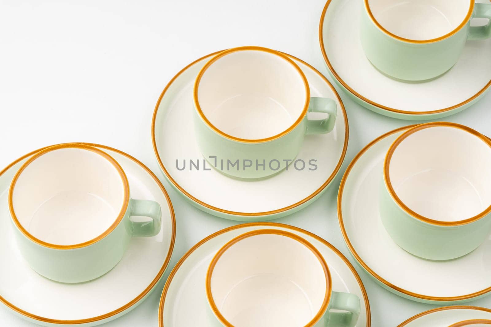 A set of white and pastel green ceramic teacups with orange outlines