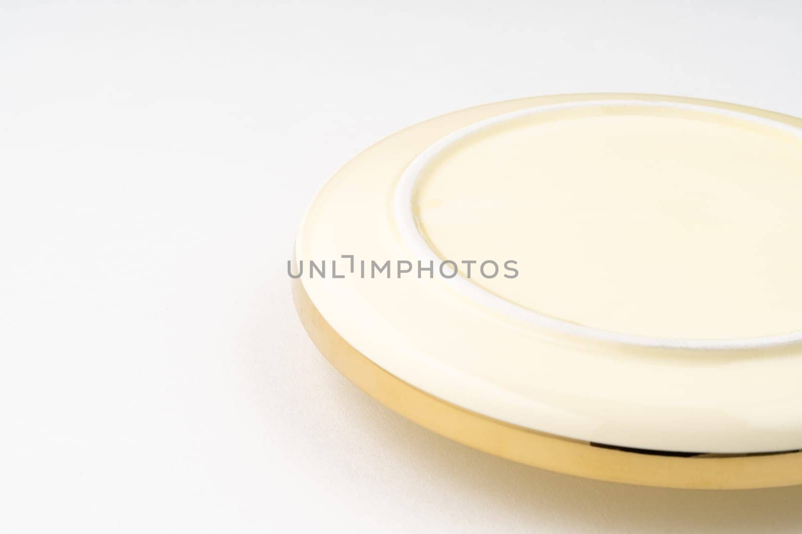 A closeup shot of the underside of a golden plate on a white background by A_Karim