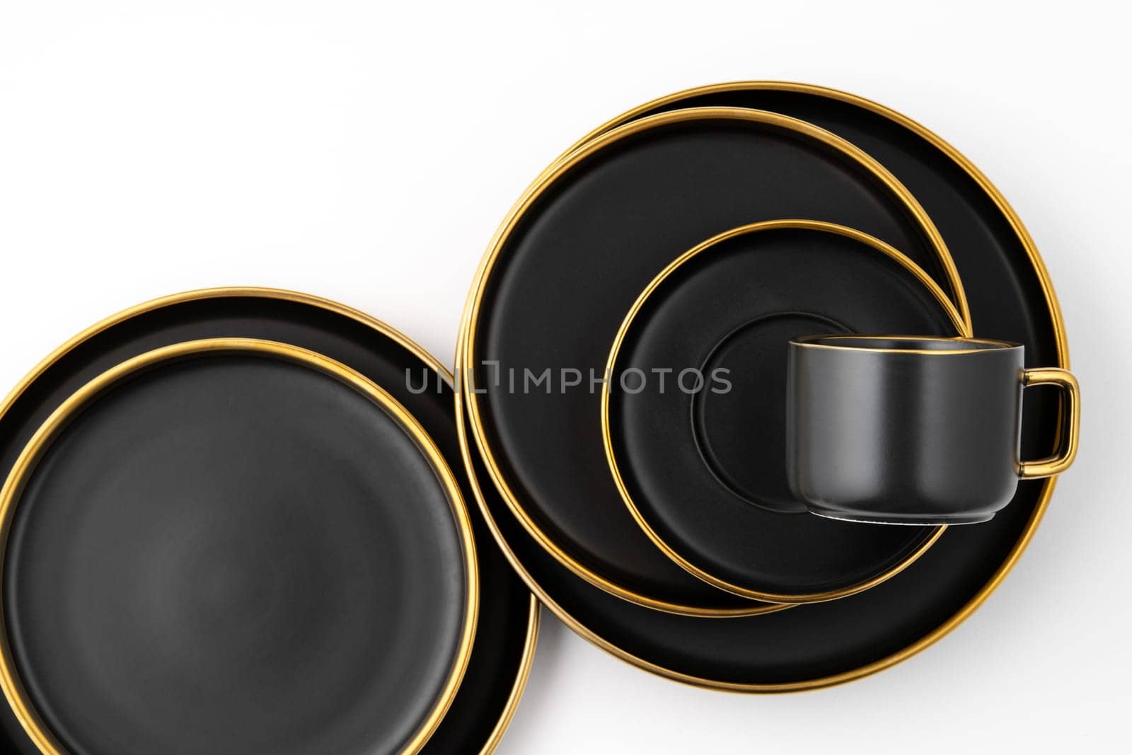 A set of black and golden ceramic plates and cup on a white background. Top view