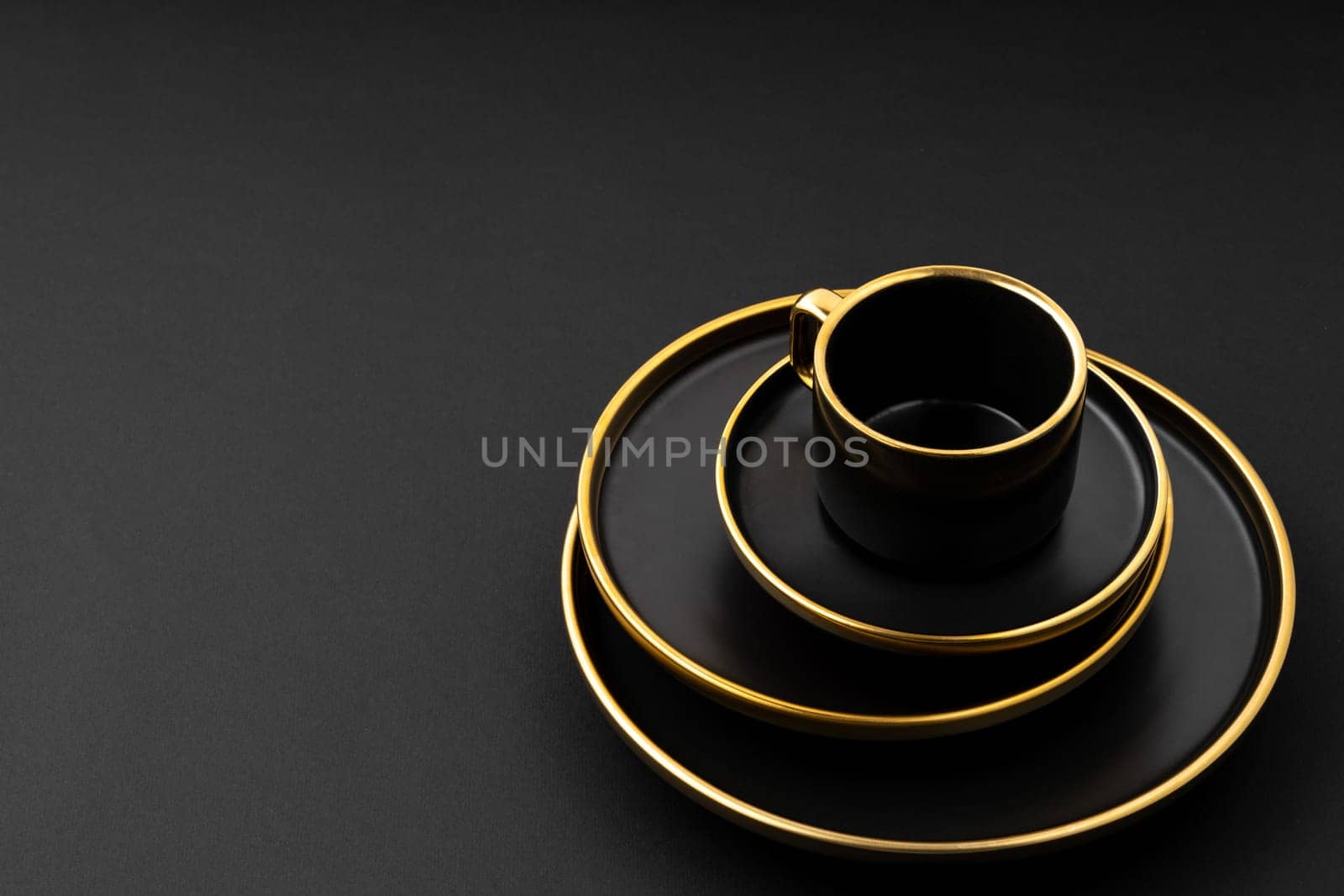 A set of black and golden ceramic plates and cup on a black background